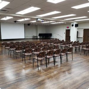 Community Room. Many chairs facing a white projection screen. Wood floors.