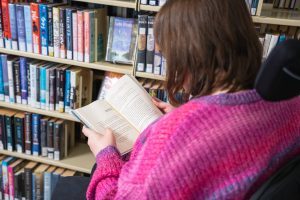 Women in pink sweater reading a book.